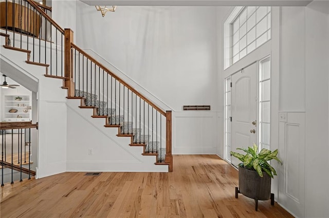 foyer with stairs, a high ceiling, wood finished floors, and a decorative wall