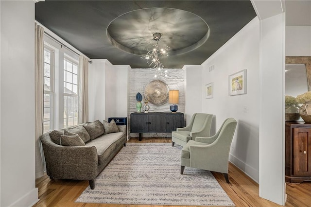 living area with wood finished floors, a raised ceiling, visible vents, and baseboards