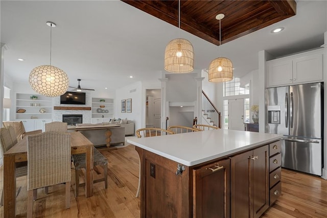 kitchen with stainless steel fridge, a glass covered fireplace, wood ceiling, light wood-type flooring, and built in shelves