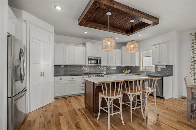 kitchen featuring stainless steel appliances, a tray ceiling, and white cabinets