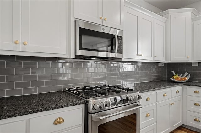 kitchen featuring stainless steel appliances, tasteful backsplash, dark stone countertops, and white cabinets