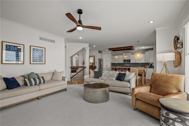 living area with attic access, decorative columns, visible vents, ornamental molding, and recessed lighting