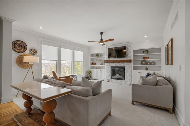 living area with ornamental molding, a fireplace, built in shelves, and baseboards