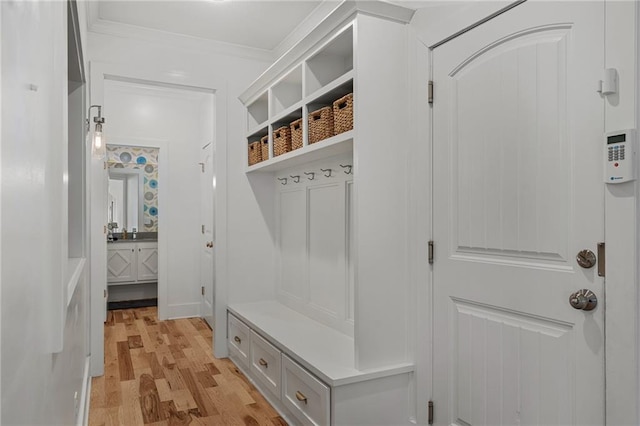 mudroom with light wood-style floors and crown molding