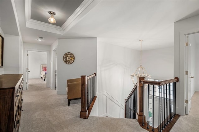 hall with carpet floors, a tray ceiling, an upstairs landing, and crown molding