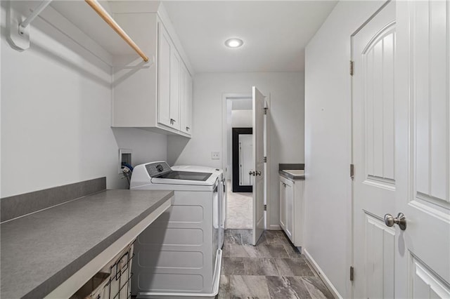 washroom with baseboards, cabinet space, and washer and dryer