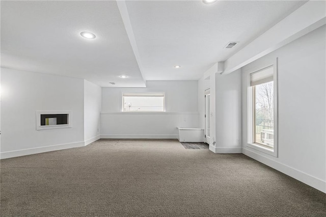 carpeted empty room featuring visible vents, a fireplace, baseboards, and recessed lighting