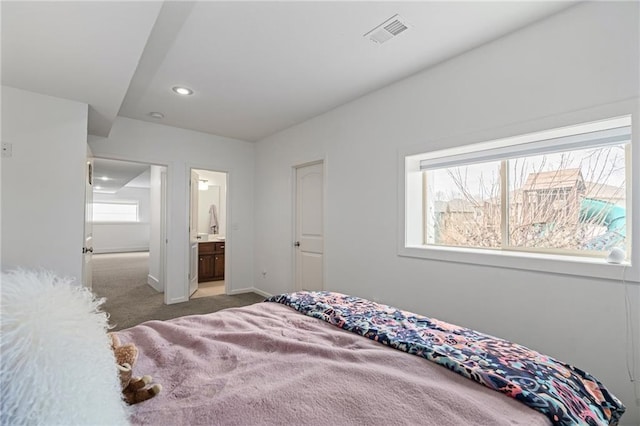 bedroom with baseboards, visible vents, ensuite bath, carpet floors, and recessed lighting