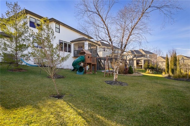 rear view of property featuring a residential view, a playground, a yard, and stucco siding