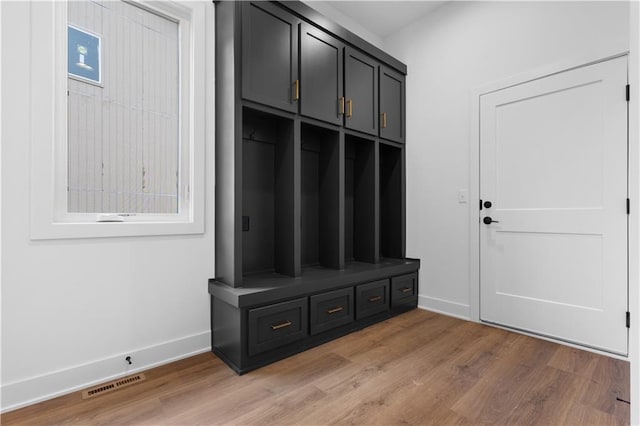 mudroom featuring baseboards, visible vents, and wood finished floors