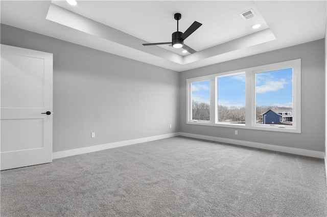 empty room featuring visible vents, a tray ceiling, baseboards, and carpet flooring