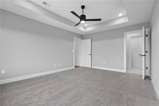 unfurnished bedroom featuring light carpet, baseboards, visible vents, and a raised ceiling