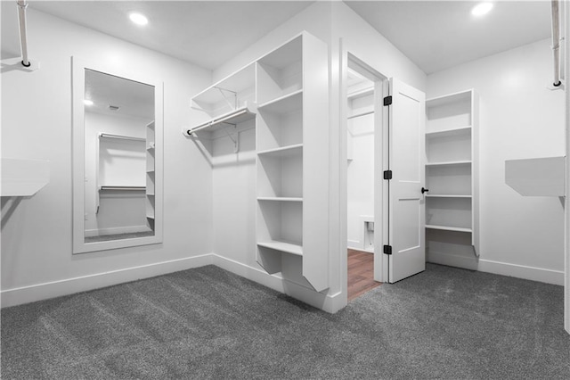 walk in closet featuring dark carpet