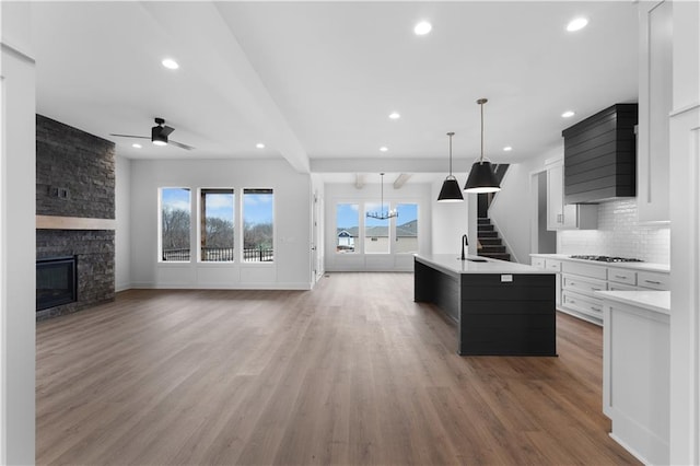 kitchen featuring a kitchen island with sink, white cabinetry, open floor plan, and light countertops