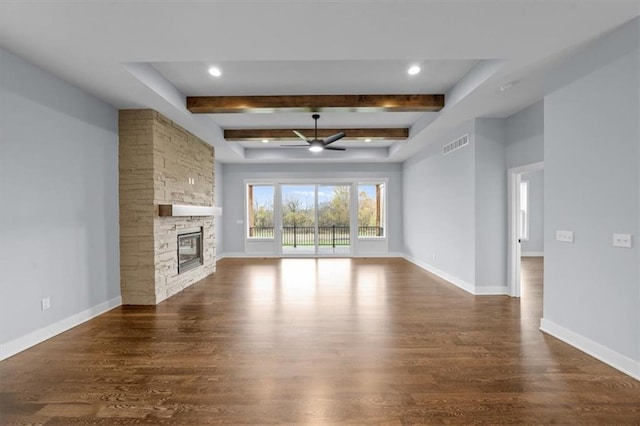 unfurnished living room with beam ceiling, a stone fireplace, ceiling fan, and dark hardwood / wood-style flooring