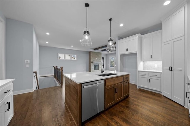 kitchen with a sink, white cabinetry, light countertops, stainless steel dishwasher, and a center island with sink