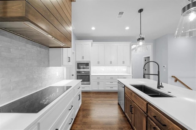 kitchen featuring stainless steel appliances, premium range hood, a sink, white cabinets, and light countertops