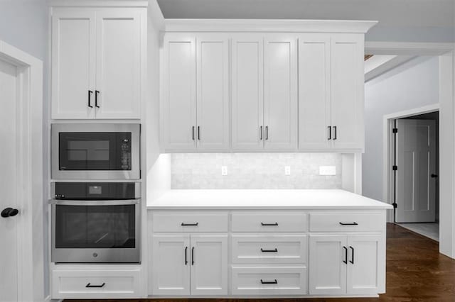 kitchen featuring white cabinetry, built in microwave, light countertops, and oven