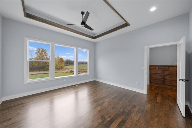 unfurnished bedroom with baseboards, dark wood finished floors, a ceiling fan, a raised ceiling, and recessed lighting