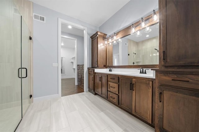 full bath featuring a sink, visible vents, baseboards, double vanity, and a stall shower