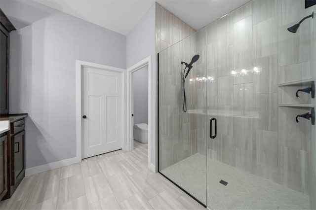 full bathroom with a stall shower, baseboards, vanity, and toilet