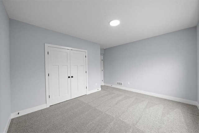 unfurnished bedroom featuring carpet floors, a closet, visible vents, and baseboards