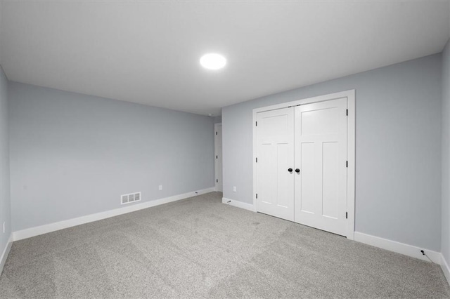 unfurnished bedroom with light carpet, visible vents, baseboards, and a closet