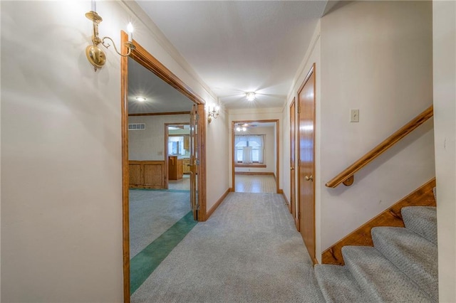 hall with ornamental molding and light carpet