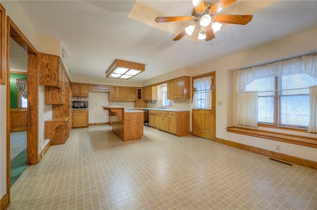 kitchen featuring sink, a center island, ceiling fan, decorative backsplash, and black appliances