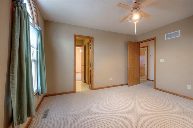 unfurnished bedroom featuring ceiling fan, ensuite bath, and light carpet