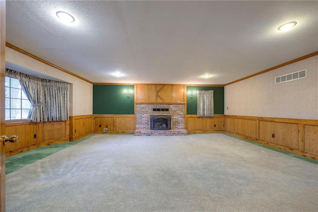 unfurnished living room with a brick fireplace, crown molding, wooden walls, and light colored carpet