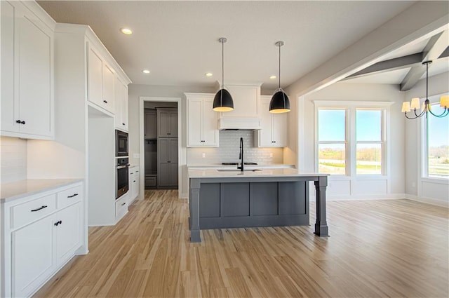 kitchen featuring black microwave, light countertops, stainless steel oven, and white cabinetry