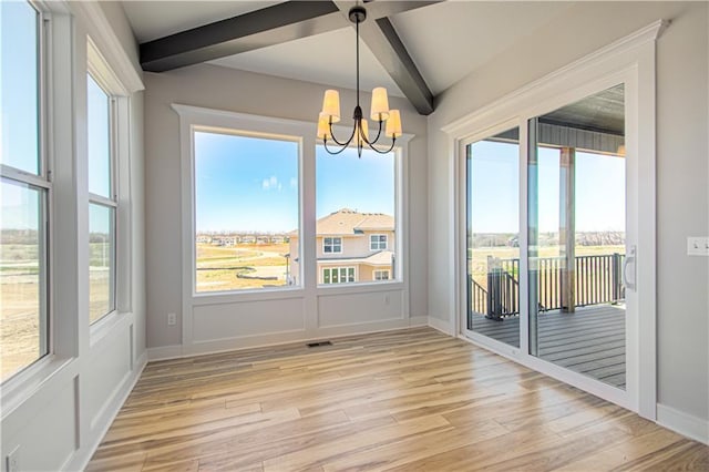 unfurnished dining area featuring light wood-style floors, baseboards, a chandelier, and beam ceiling