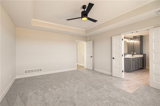 unfurnished bedroom with light carpet, baseboards, visible vents, and a raised ceiling