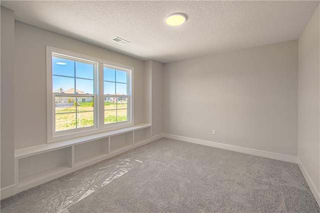 empty room featuring baseboards, a textured ceiling, visible vents, and carpet flooring