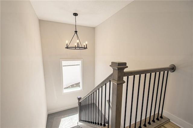 staircase featuring an inviting chandelier and baseboards