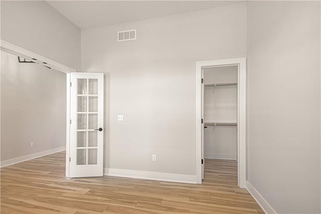 unfurnished bedroom featuring light wood-style flooring, a spacious closet, and visible vents