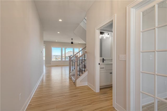 hallway with light wood-style floors, recessed lighting, stairway, and baseboards