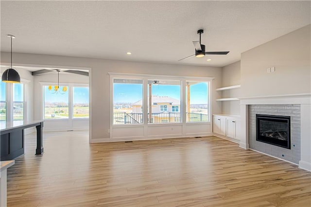 unfurnished living room featuring a ceiling fan, light wood-type flooring, a brick fireplace, and recessed lighting