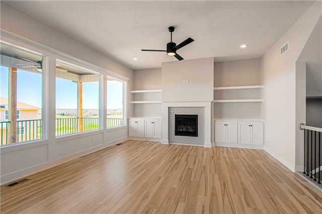 unfurnished living room featuring light wood-style flooring, a brick fireplace, and visible vents