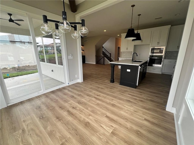 1712 SW Arbormist Dr, Lees Summit, MO 64082 - kitchen featuring appliances with stainless steel finishes, open floor plan, decorative backsplash, light wood-style floors, and a kitchen breakfast bar