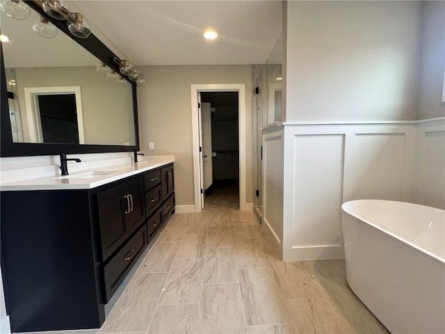 1712 SW Arbormist Dr, Lees Summit, MO 64082 - bathroom featuring a freestanding tub, double vanity, marble look tiles, a decorative wall, and a wainscoted wall