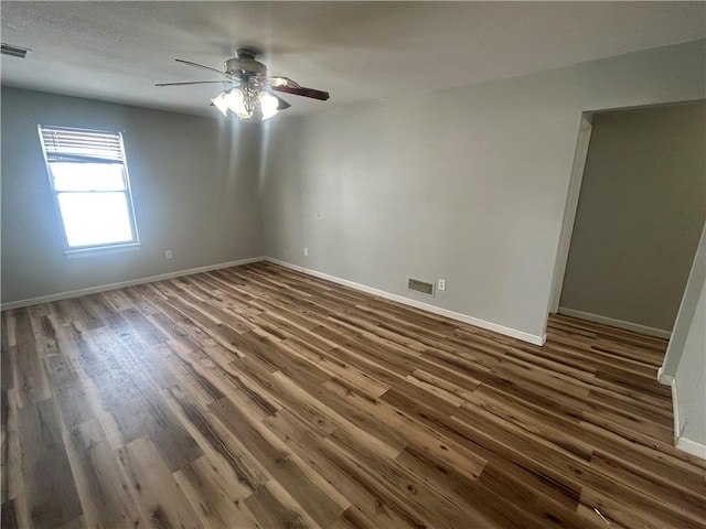 spare room with dark hardwood / wood-style flooring and ceiling fan