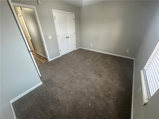 unfurnished bedroom with dark carpet and a closet