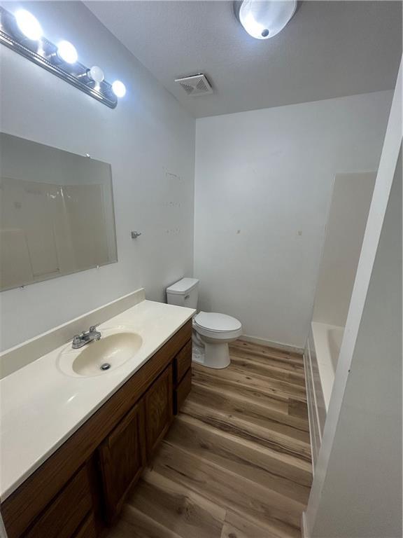 full bathroom featuring vanity, toilet, wood-type flooring, and plus walk in shower