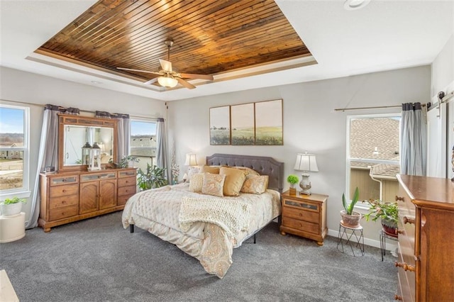 bedroom featuring ceiling fan, a tray ceiling, and dark colored carpet