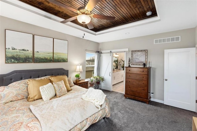 bedroom with ceiling fan, ensuite bathroom, a raised ceiling, and carpet flooring