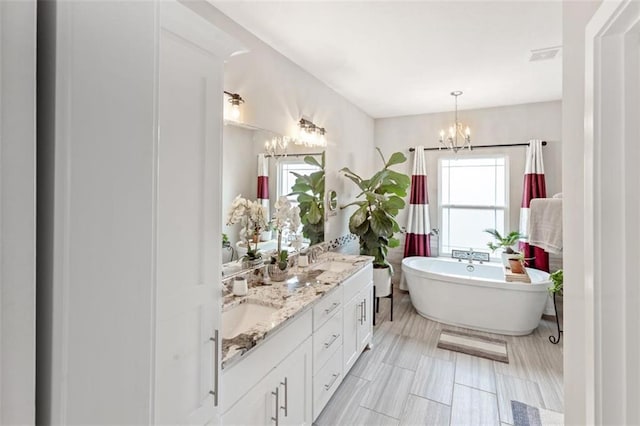 bathroom featuring a bathing tub, a chandelier, and vanity