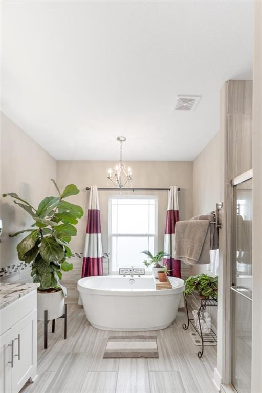 bathroom with separate shower and tub, a chandelier, and vanity