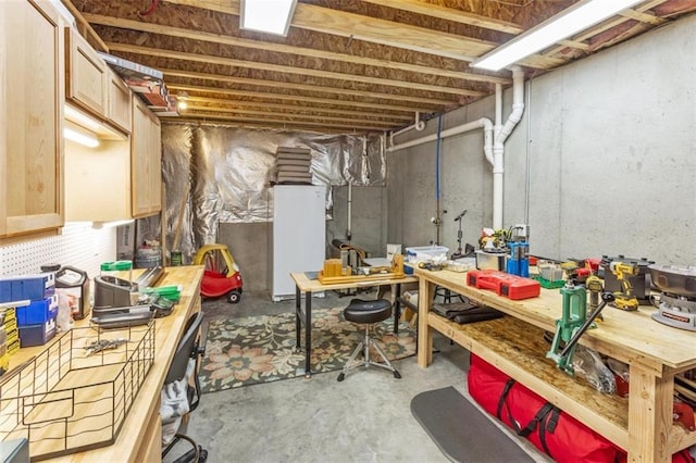 basement featuring a workshop area and white fridge